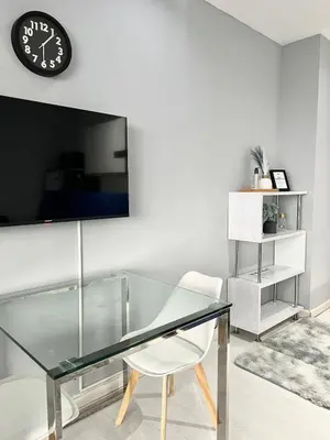 a glass table with a chair and a clock on a wall at Affordable Suite at Gramercy Makati with Balcony & Parking in Manila