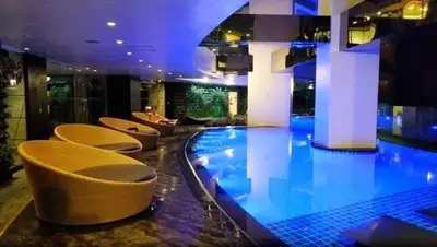 a large swimming pool in a building with chairs at Affordable Suite at Gramercy Makati with Balcony & Parking in Manila