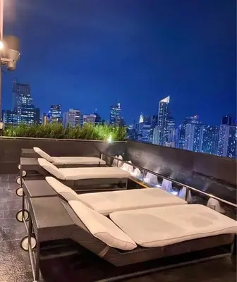 a row of chaise lounges on a rooftop with a city skyline at Affordable Suite at Gramercy Makati with Balcony & Parking in Manila