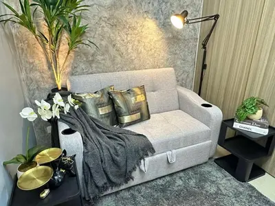 a living room with a couch with pillows and a blanket at Sakura Suites At Mall of Asia Near Airport in Manila