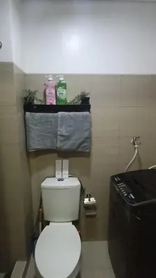 a bathroom with a toilet and towels on a shelf at Shore residences tower A in Manila