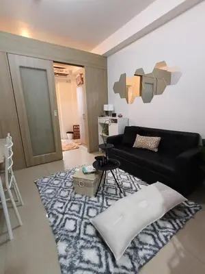 a living room with a black couch and a rug at Shore residences tower A in Manila