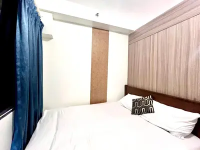 a bedroom with a white bed with a blue curtain at Very Central Mall of Asia Manila Apartment in Manila
