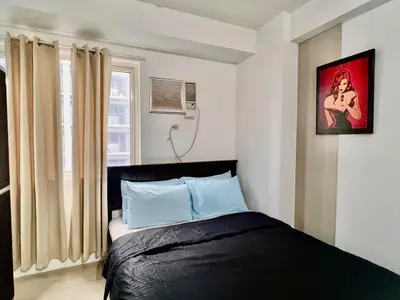 a bedroom with a bed and a window at Very Central Mall of Asia Manila Apartment in Manila