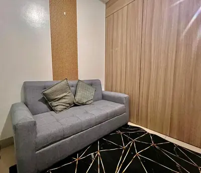 a grey couch in a room with a wall at MOA - Walking Distance to Mall Cheap Accommodation in Manila