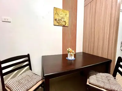 a dining room table with two chairs and a vase of flowers at MOA - Walking Distance to Mall Cheap Accommodation in Manila