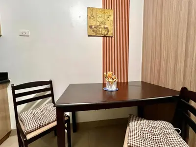 a dining room table with a vase of flowers on it at MOA - Pasay Cheap Accommodation in Manila