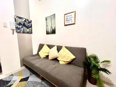 a couch in a living room with yellow pillows at Mall of Asia Shore Residence - Perfect Location in Manila