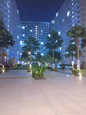 a park with palm trees and buildings at night at Mall of Asia Shore Residence - Perfect Location in Manila