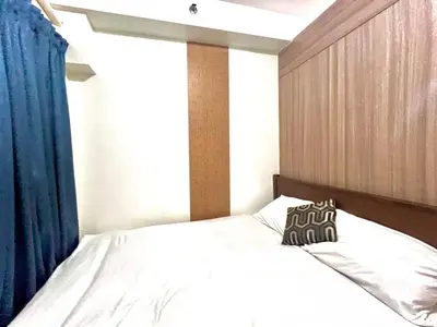 a bedroom with a white bed with a blue curtain at Mall of Asia Shore Residence - Perfect Location in Manila