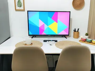 a computer monitor sitting on top of a desk with two chairs at Mall of Asia - Aseana Nice and Cheap Apartment in Manila