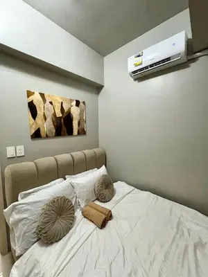 a bed with white sheets and two pillows on it at Stylish Comfy and Cozy in Manila