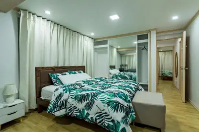 a bedroom with a bed with a green and white blanket at Modern 4BR House with Billiards,KTV,WIFI,Netflix-10mins from Robinson Mall in Manila