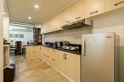 a kitchen with a stainless steel refrigerator and wooden cabinets at Modern 4BR House with Billiards,KTV,WIFI,Netflix-10mins from Robinson Mall in Manila