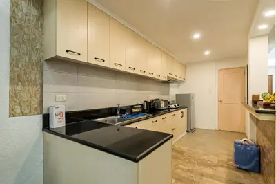 a kitchen with white cabinets and a black counter top at Modern 4BR House with Billiards,KTV,WIFI,Netflix-10mins from Robinson Mall in Manila
