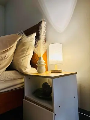 a bed with a table with a lamp on it at 2BR condo unit near BGC in Manila