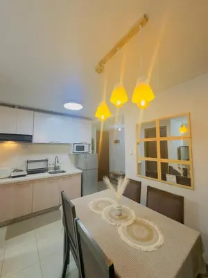 a kitchen with a table with chairs and yellow lights at 2BR condo unit near BGC in Manila