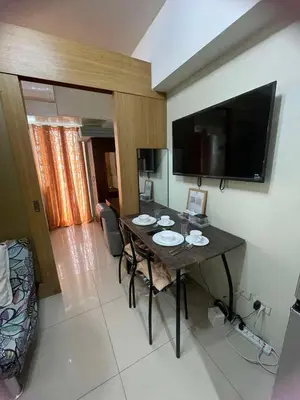 a dining room with a table with chairs and a television at 1441-Pool view 1BR 1 sofa Bed 1 Extra mattress in Manila