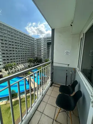 a balcony with two chairs and a view of a building at Shell Residences pool view in Manila