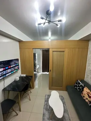 a living room with a couch and a table at Shell Residences pool view in Manila