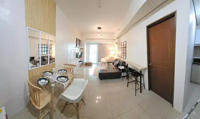 a living room and a dining room with a table at Beacon Makati Skyline View in Manila