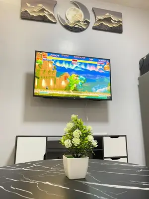 a television on a wall above a table with a plant at Dandelion Shore Residences 1BR in Manila