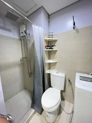 a small bathroom with a toilet and a shower at Dandelion Shore Residences 1BR in Manila