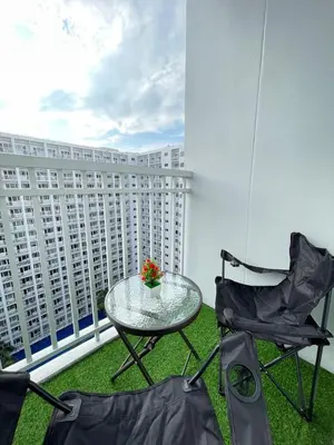 a glass table and chairs on a balcony with buildings at Dandelion Shore Residences 1BR in Manila