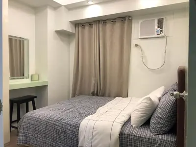 a bedroom with a bed and a window with a fan at 1 BR Condo in Quezon City at Avida New Manila in Manila