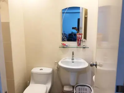 a bathroom with a toilet and a sink and a mirror at 1 BR Condo in Quezon City at Avida New Manila in Manila