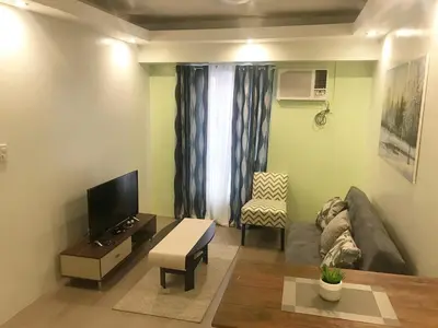 a living room with a couch and a tv at 1 BR Condo in Quezon City at Avida New Manila in Manila