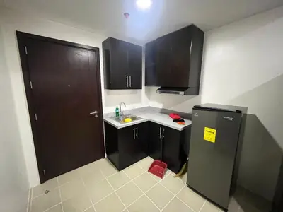 a small kitchen with black cabinets and a refrigerator at Covent Garden Condo 2117 in Manila