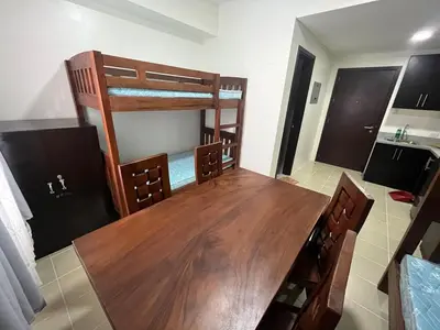 a room with a wooden table and bunk beds at Covent Garden Condo 2117 in Manila