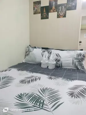 a bed with a black and white comforter on it at Verlyn Place At Sea Residences Near Moa in Manila
