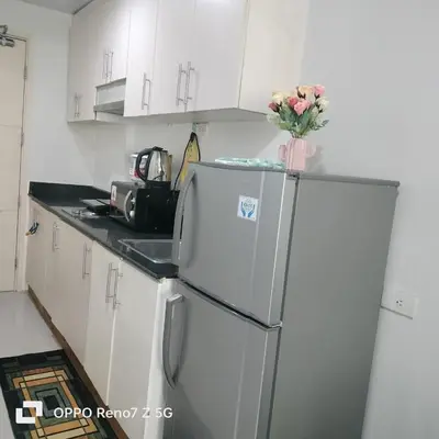 a kitchen with a refrigerator with a vase of flowers on it at Verlyn Place At Sea Residences Near Moa in Manila