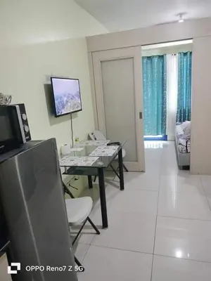 a living room with a table and a television at Verlyn Place At Sea Residences Near Moa in Manila