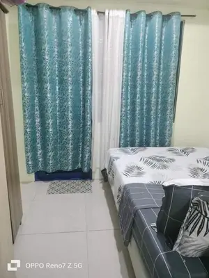 a bedroom with two beds and blue curtains at Verlyn Place At Sea Residences Near Moa in Manila