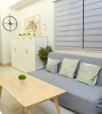 a living room with a blue couch and a wooden table at Awesome Corner at Shore 3 Mall of Asia near Airport in Manila