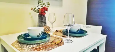 a table with two plates and glasses on it at Air Residence Makati Cozy City View in Manila