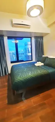 a bedroom with a bed and a large window at Air Residence Makati Cozy City View in Manila