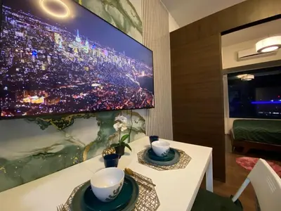 a room with a tv on a wall with a table with two cups at Air Residence Makati Cozy City View in Manila