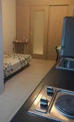 a kitchen with a stove with a sink and a bed at Shore Tower B in Manila