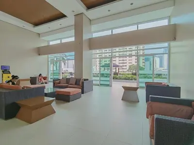 a large lobby with couches and tables and windows at The Beacon Condo at Makati CBD in Manila