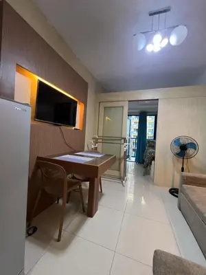 a living room with a table and a tv on a wall at MNM Place - Sea Residence 5A in Manila