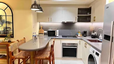 a kitchen with white cabinets and a table and chairs at 3 Bedroom Beautiful and Spacious Penthouse in Makati in Manila