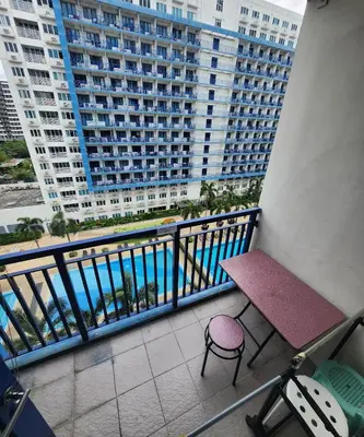 a balcony with a table and chairs and a large building at MNM Place - Sea Residence 9A in Manila