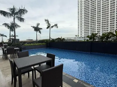 a swimming pool with tables and chairs next to a building at 2 Br Condo Apartment near PICC, CCP, WTC & Star City at Coast Residences, Pasay City in Manila
