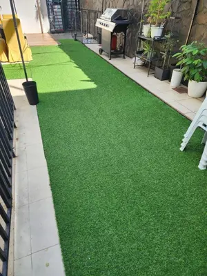 a garden with green grass on the side of a building at Family room with private pool in Manila