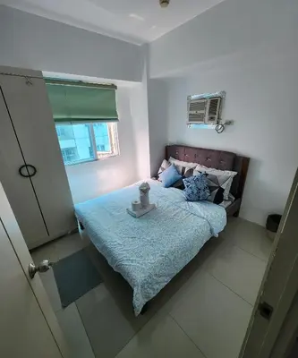 a bedroom with a bed with a blue comforter at MNM Place - Sea Residence 0F in Manila