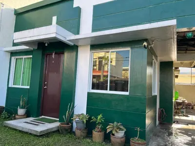 a green house with a red door and potted plants at NRD Staycation Transient House in Dasmariñas
